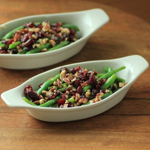 2 white serving dishes with Green Beans with Pecans and Cranberries in them