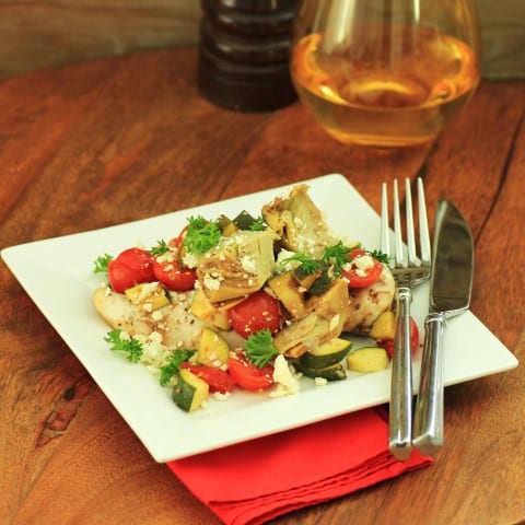 Mediterranean Chicken Bake on a square white plate with a knife and fork.