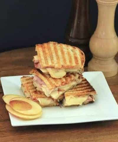 Apple Brie and Ham Panini sandwich cut in half and stacked on a small white plate