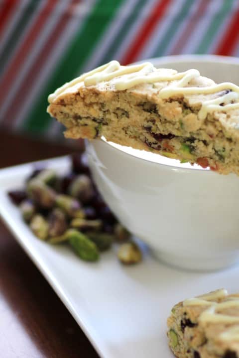 Cranberry Pistachio Biscotti sitting on the rim of a coffee cup