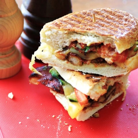 Shrimp Club Panini cut in half and stacked up sitting on a red cutting board