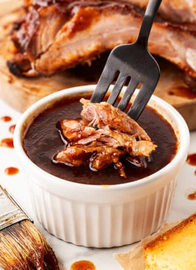 Dipping pieces of pork into extra BBQ sauce.