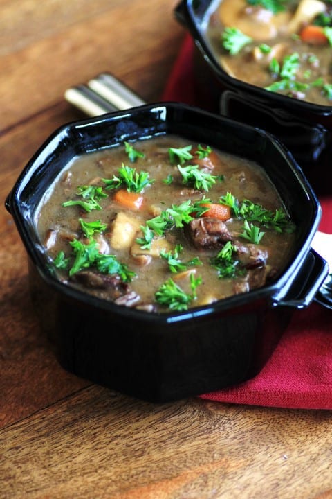 Beef, Wine and Mushroom Soup in a black serving bowl on a wooden table