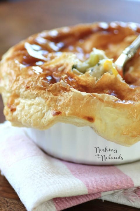 Individual chicken pot pie in a white bowl on a white and pink napkin with a spoon in the bowl