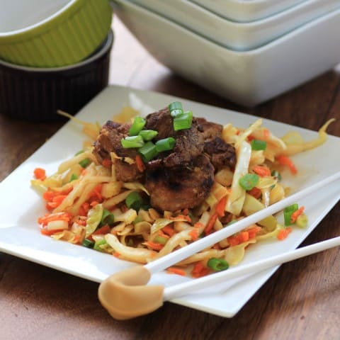 Korean Pork Tenderloin Medallions over Asian Slaw served on a white plate with chop sticks