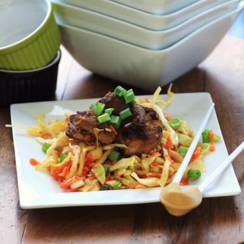 Korean Pork Tenderloin Medallions over Asian Slaw served on a white plate with chop sticks