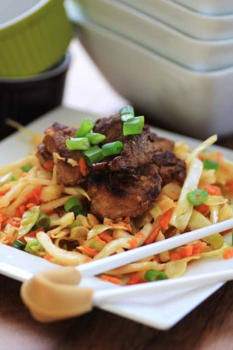 Korean Pork Tenderloin Medallions with Asian Slaw on a white plate with chop sticks