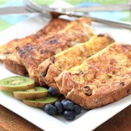 Panettone French toast on a white plate with sliced kiwi and blueberries