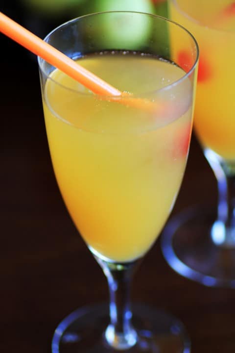 Peach Sparkler in a tall stemmed glass with a straw