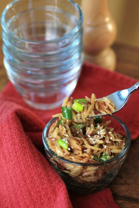 Sesame Orzo in a small glass bowl with a fork full being lifted out of the bowl