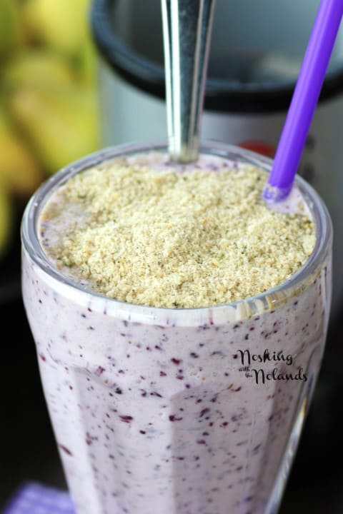 Blueberry Smoothie with Crumble Topping close up with a purple straw and a tall spoon