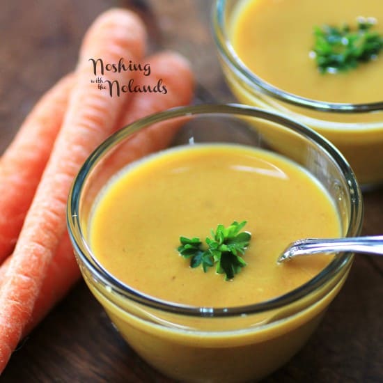 Carrot and Curry Soup in small glass bowls with a spoon and garnished with parsley
