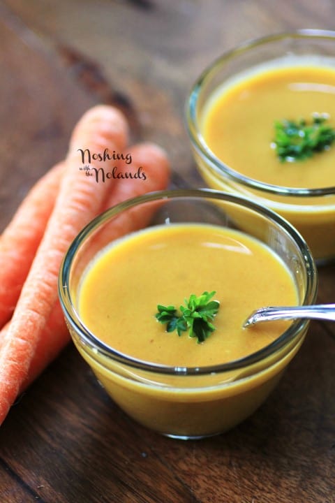 Carrot and Curry Soup in small glass bowls with a spoon and garnished with parsley