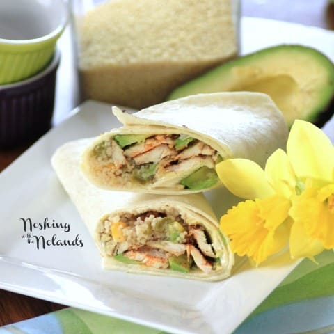 Chicken Couscous Wrap cut in half sitting on a white plate with a yellow daffodil beside the plate 