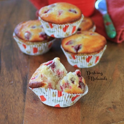 Cranberry Lemon Almond Muffins with one broken in half on a wooden cutting board