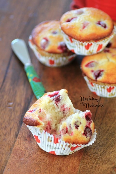 Cranberry Lemon Almond Muffins with one broken in half on a wooden cutting board