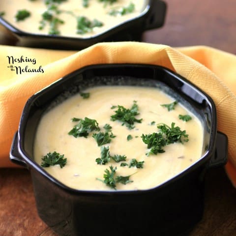 Cream of Pumpkin in a black bowl garnished with chopped parsley