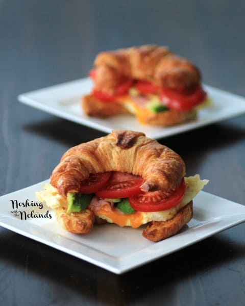 Egg Croissant with slices of tomato and avocado on a white plate 