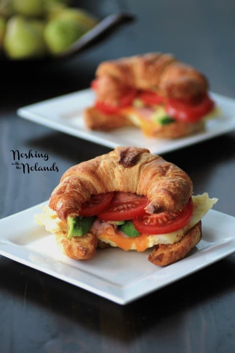 Egg Croissant with slices of tomato and avocado on a white plate