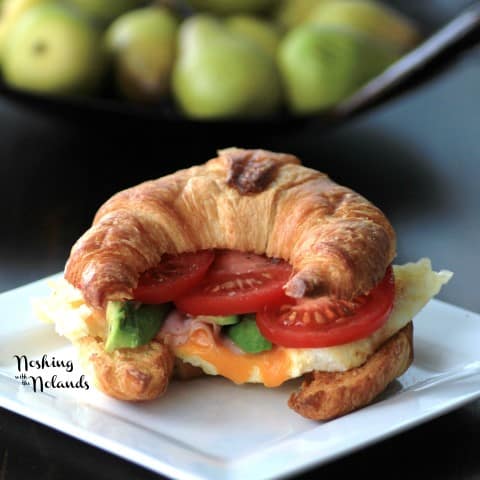 Egg Croissant on a white plate with slices of tomato and avocado