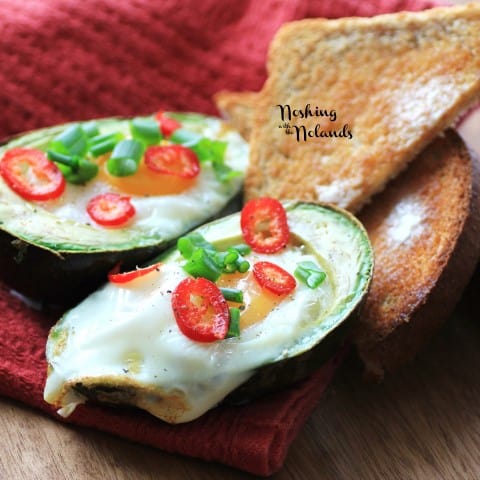 Eggs in Avocados on a wooden board and red napkin with toast
