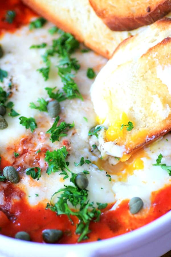 Eggs in Purgatory in a white dish with toasted dipped into the egg yolk