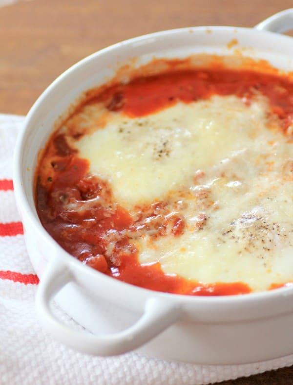 Eggs in Purgatory in a white bowl sitting on a red and white tablecloth