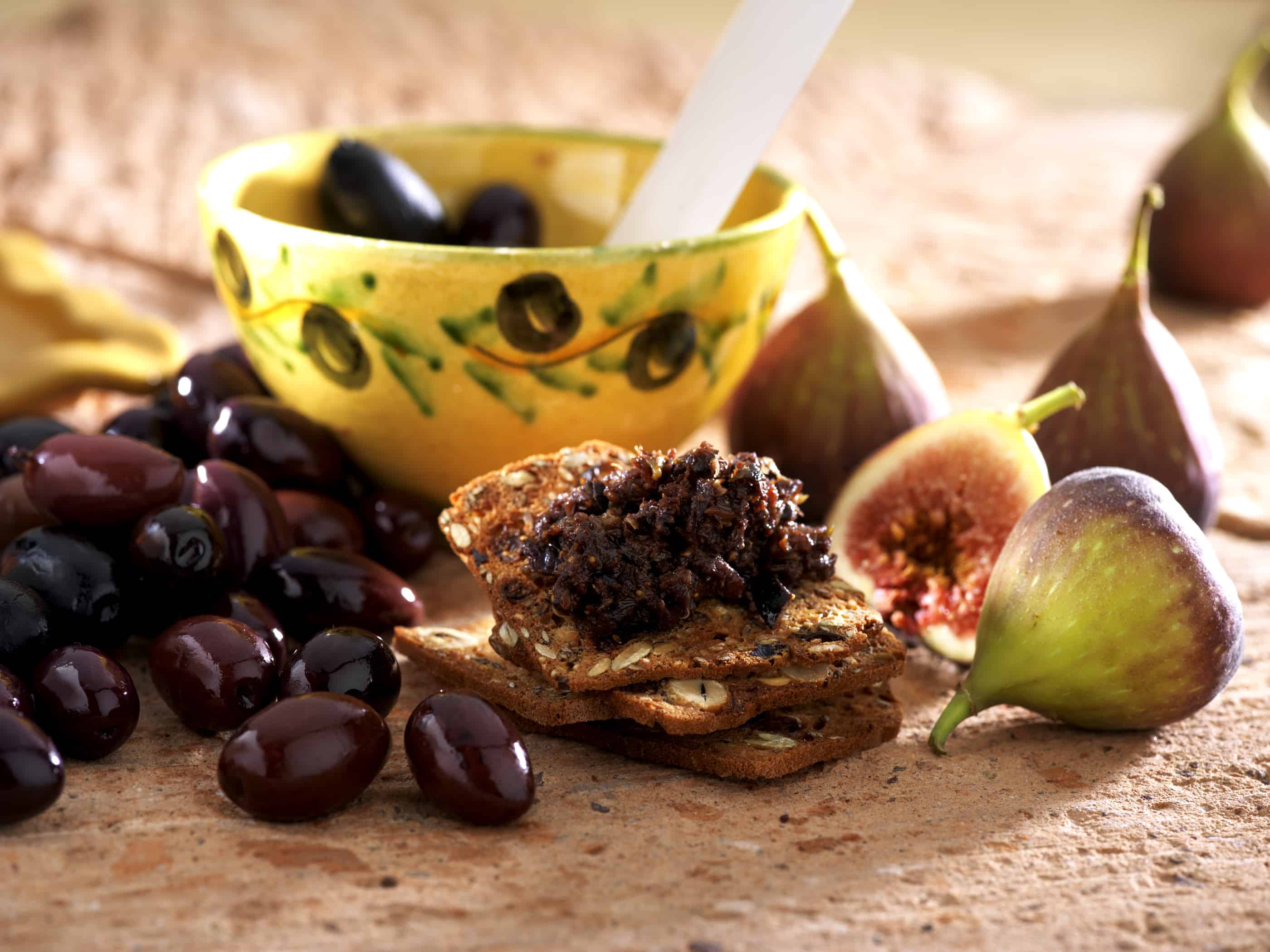 Fig Olive Tapenade on a whole grain cracker with black olives and fresh figs