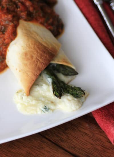 Asparagus Three Cheese Burrito on a white plate with cheese oozing out.