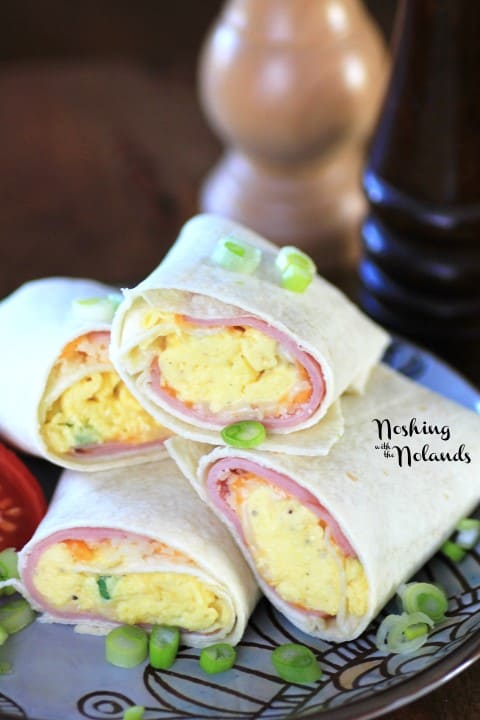 Egg Wraps cut in half and stacked on a grey and brown plate garnished with chopped green onions 