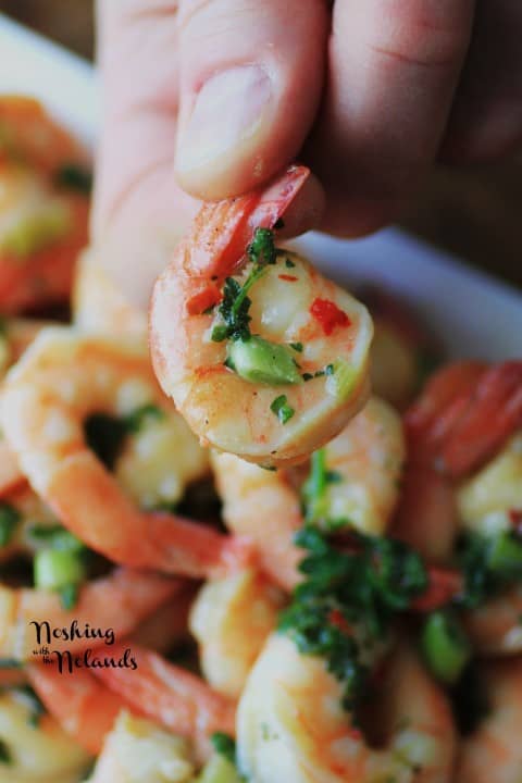 Shrimp in Mustard Sauce being held up over a plate of the shrimp