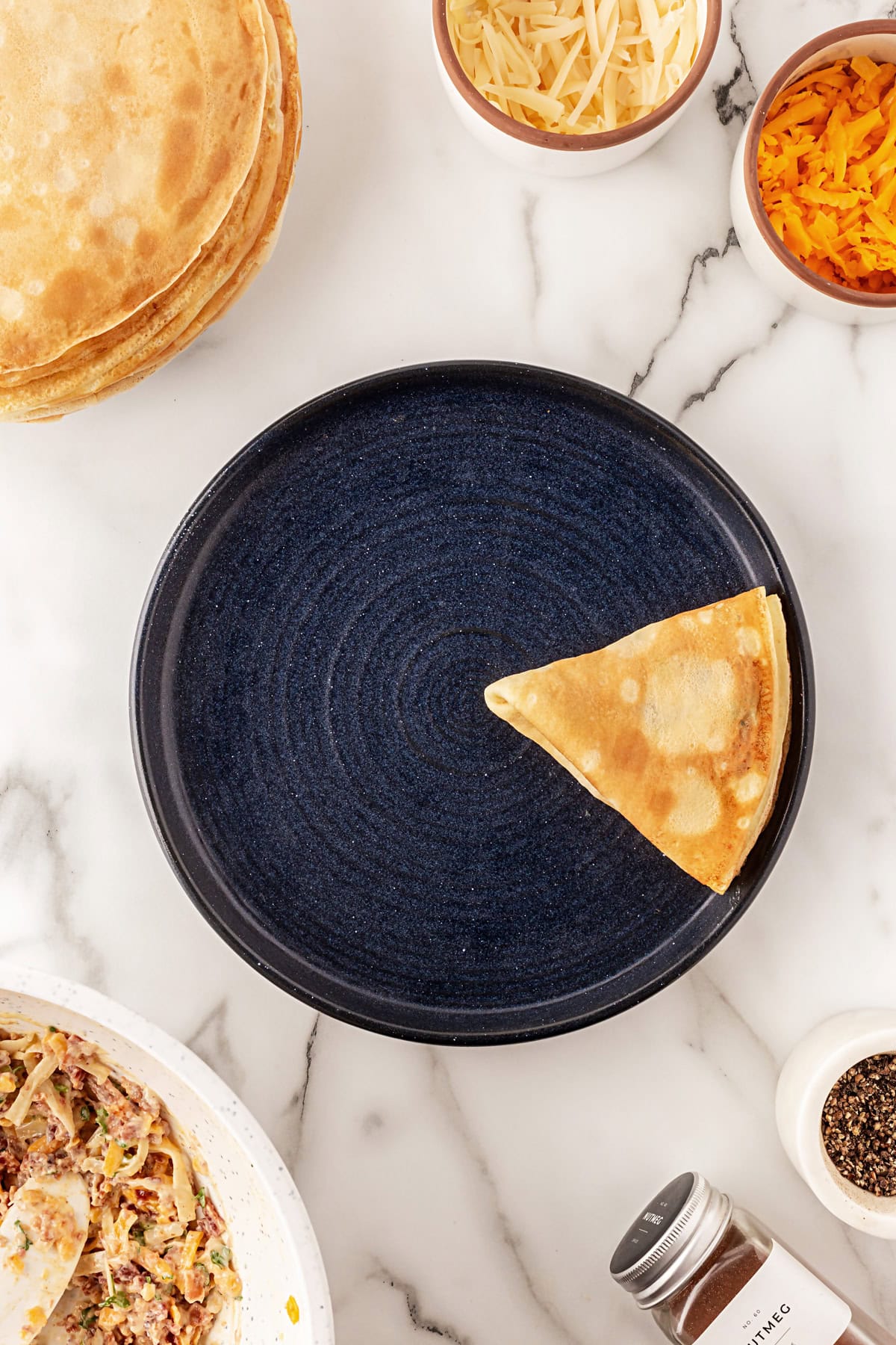 This recipe for Crepes Lorraine is a time-honored treasure that I have been making for over 40 years. Friends and family love this recipe, and I am thrilled to offer it to you also. Finished folding a crepe.