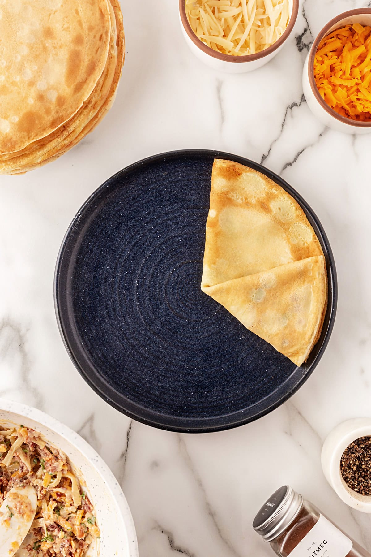 This recipe for Crepes Lorraine is a time-honored treasure that I have been making for over 40 years. Friends and family love this recipe, and I am thrilled to offer it to you also. Showing how to fold a crepe.