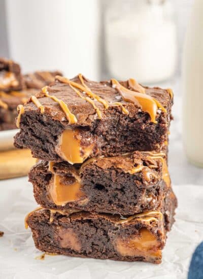Three stacked brownies with the top one having a bite taken.