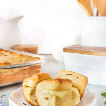 Parker House Rolls on a plate with more in the background.