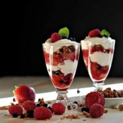 Breakfast Parfaits with berries around the tall glasses.