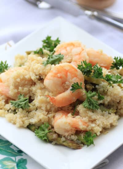 Lemony shrimp and asparagus with quinoa on a white plate.