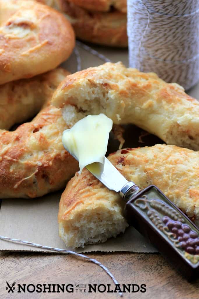 Sundried Tomato Asiago Bagels broken in half with a butter knife and butter on it