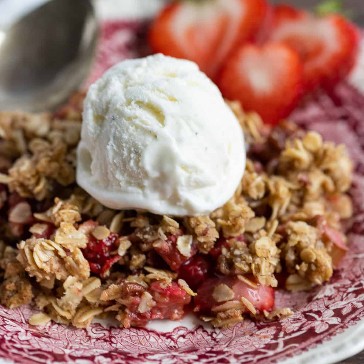 Close-up picture of ice cream on top of strawberry rhubarb crisp. 