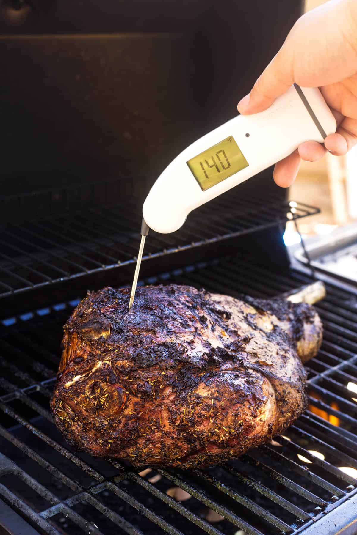 Checking the temperature of the lamb while on the grill. 