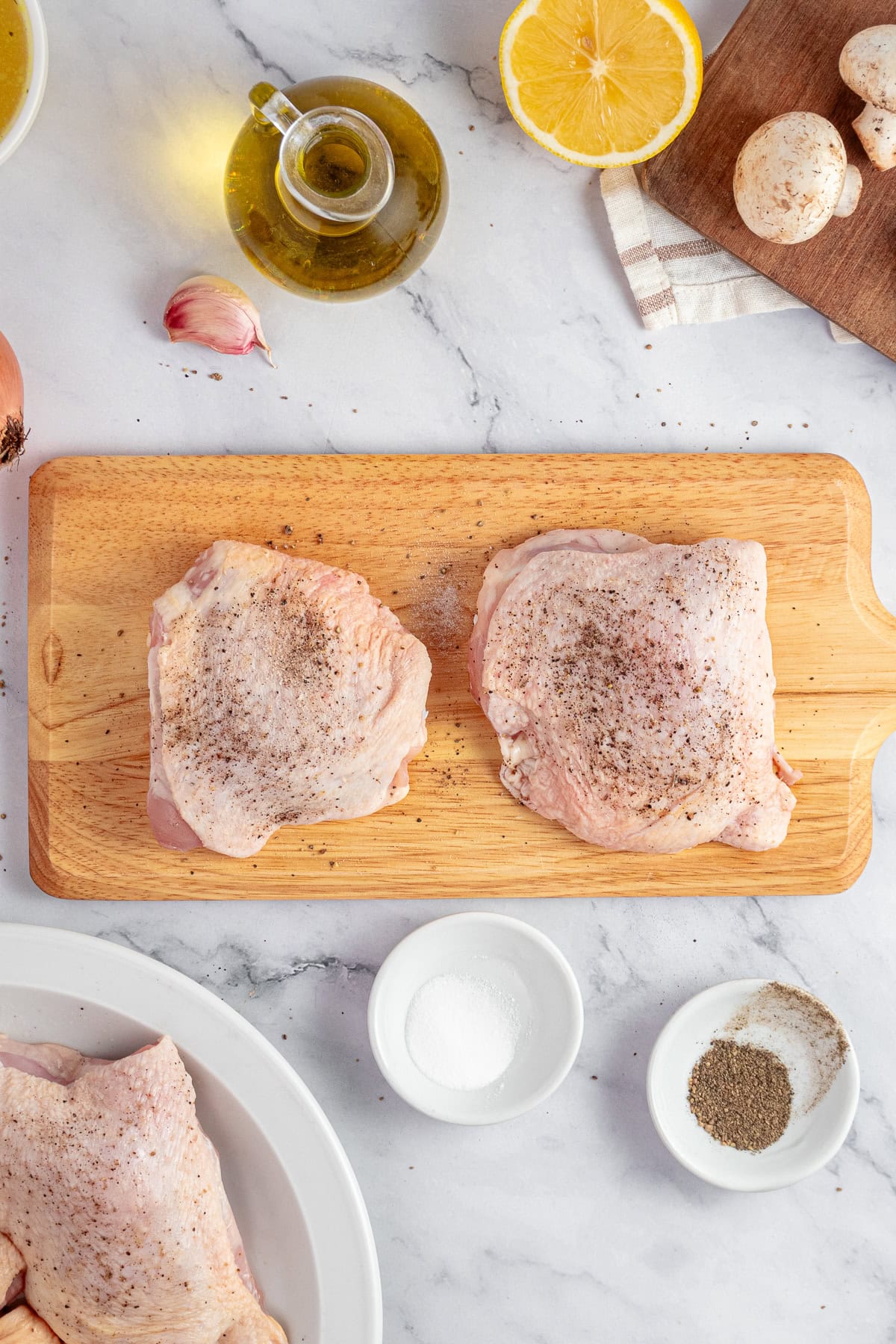 Chicken thighs seasoned with salt and pepper.