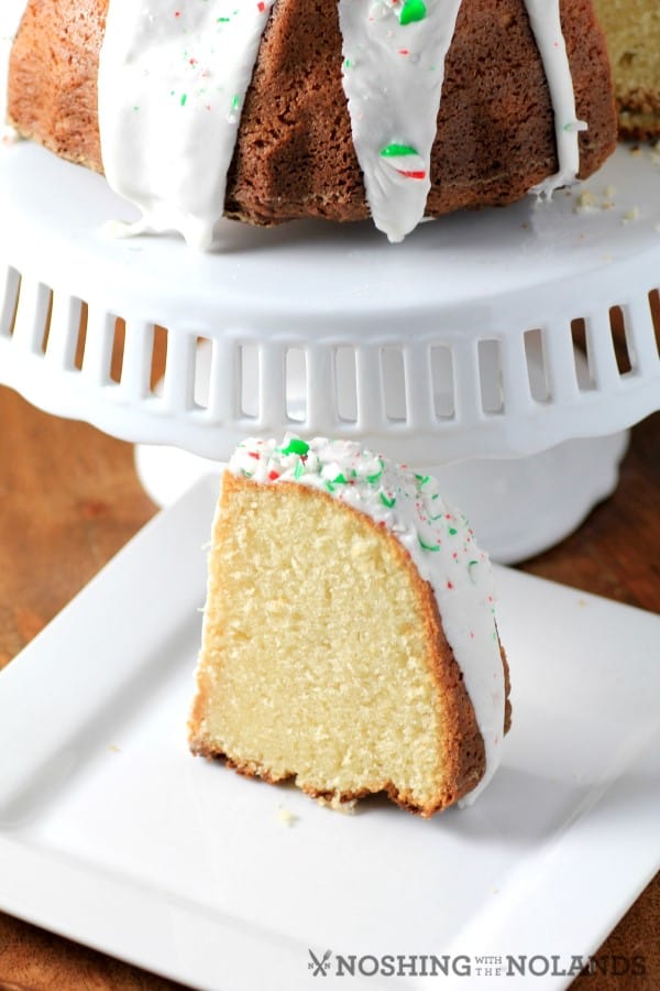 White Hot Chocolate Peppermint Bundt slice on a white plate with the reat of the cake on a white cake stand