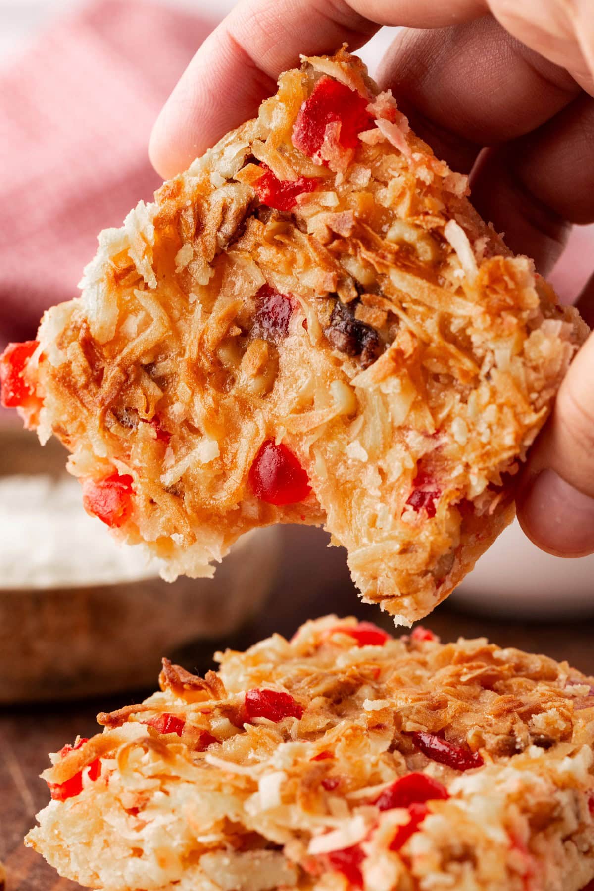 Holding a Pineapple Coconut Cherry Dream Bar with a bite taken. 