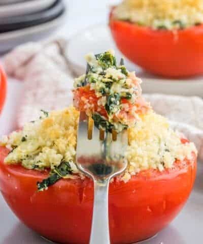 Artichoke Stuffed Tomatoes with a forkful resting on a tomate