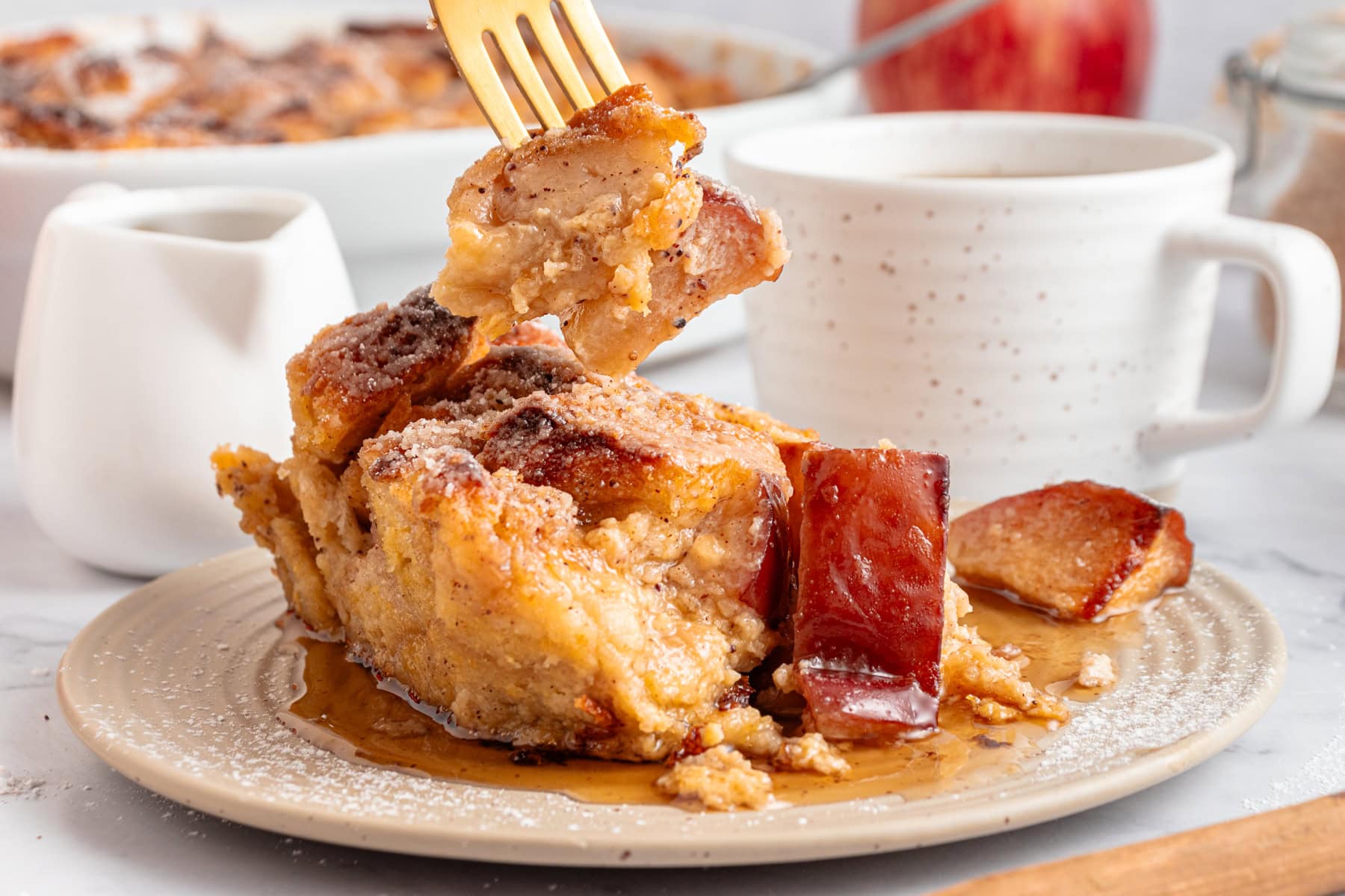 A portion of french toast casserole over a plate with maple syrup on top.