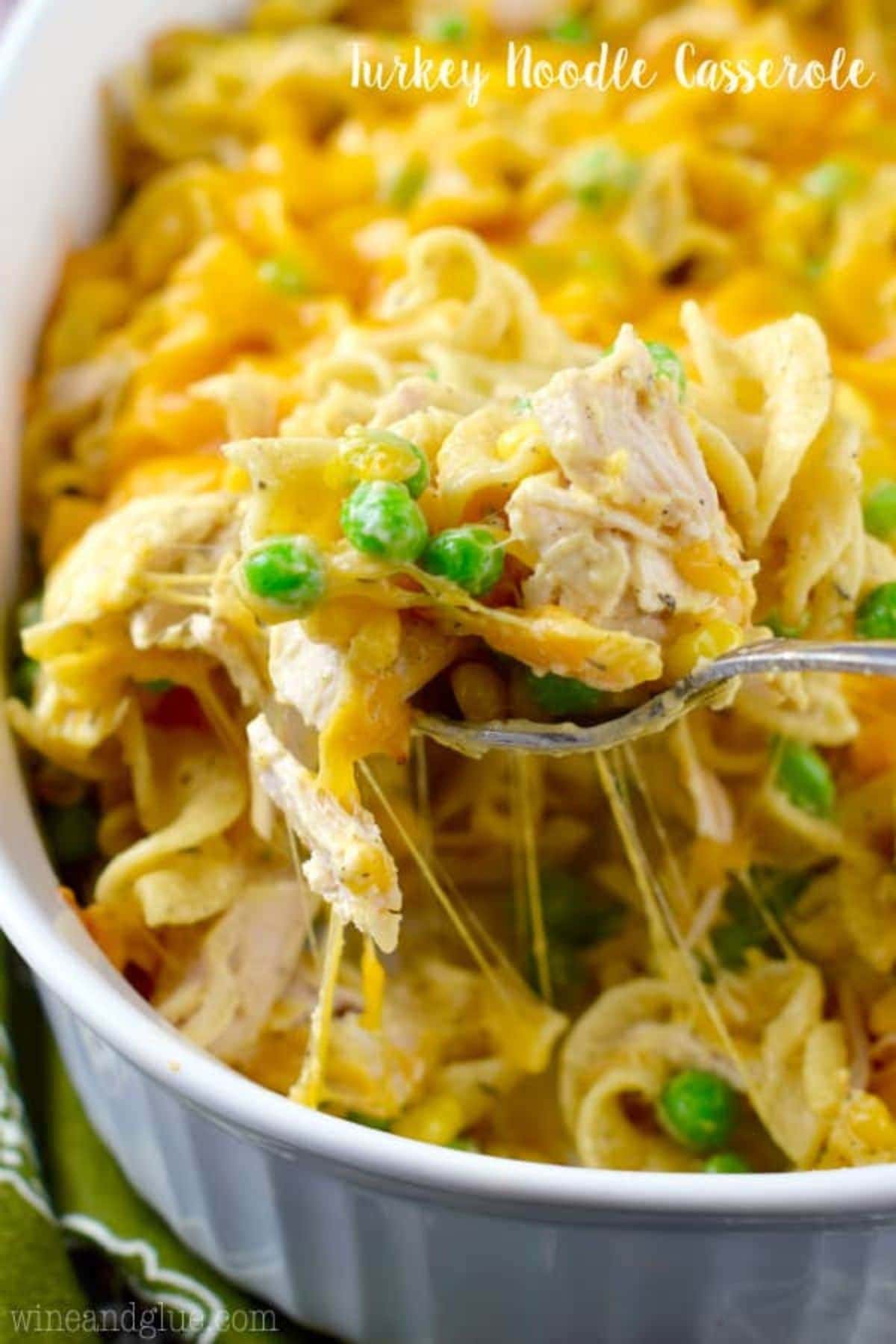 Casserole dish filled with turkey noodle casserole with a spoon removing a bite.