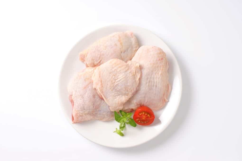 raw chicken thighs on white plate