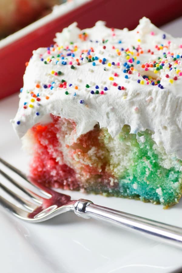 A piece of Rainbow Birthday Poke Cake with a fork