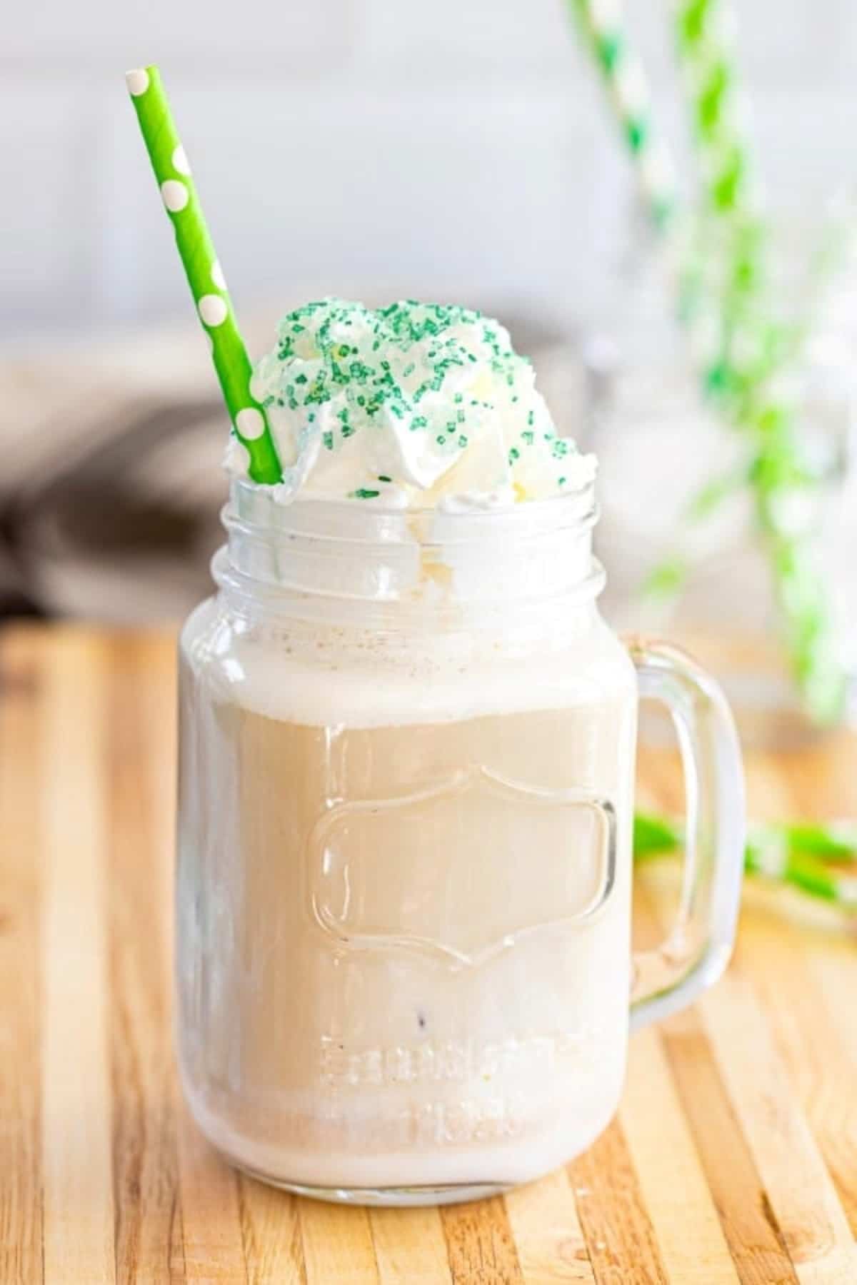 Pistachio Iced coffee served in a glass jar with a green straw.