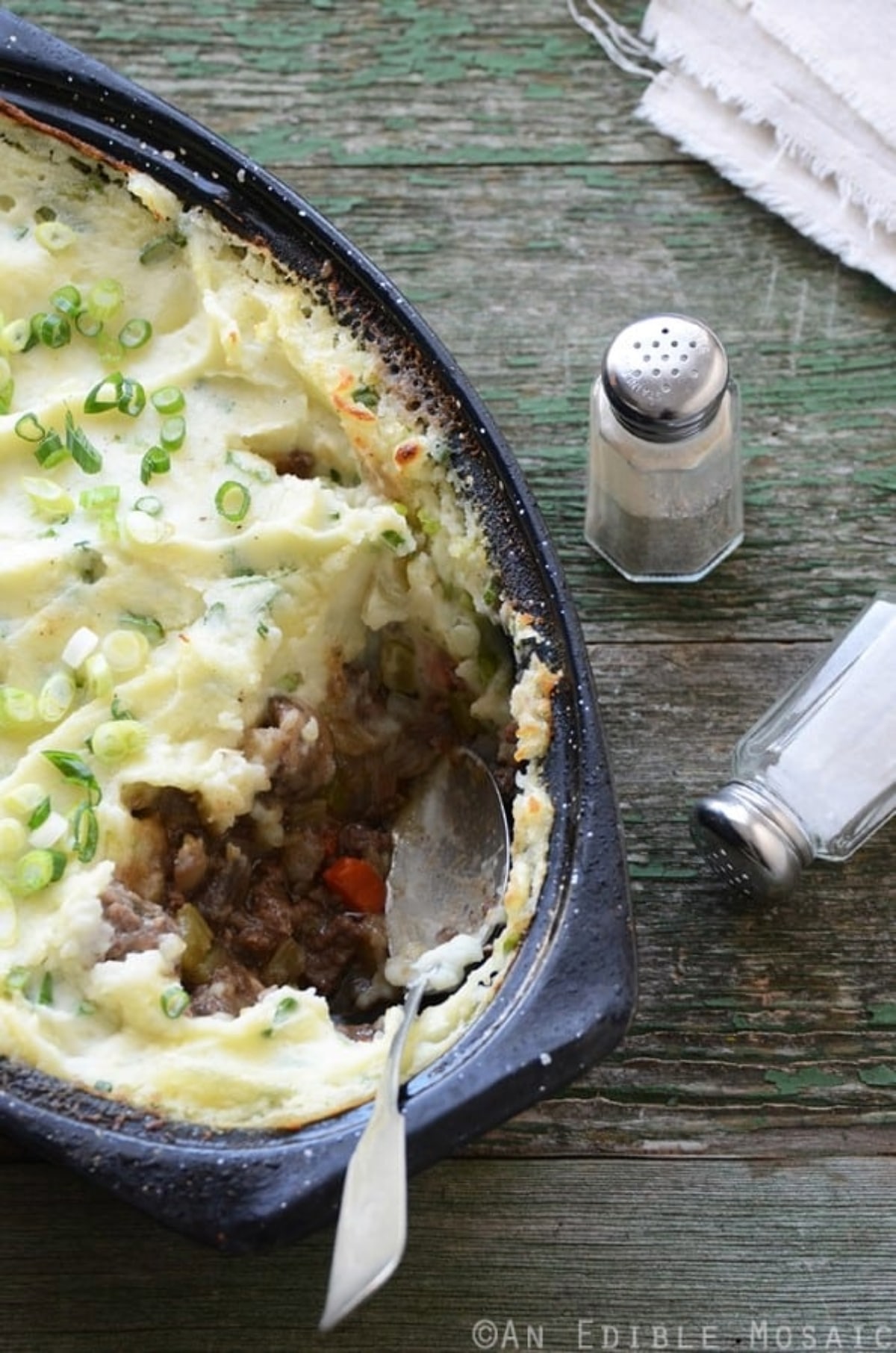 Champ Topped Vegetable Beef Guinness Casserole served in a casserole dish with salt and pepper shakers. 